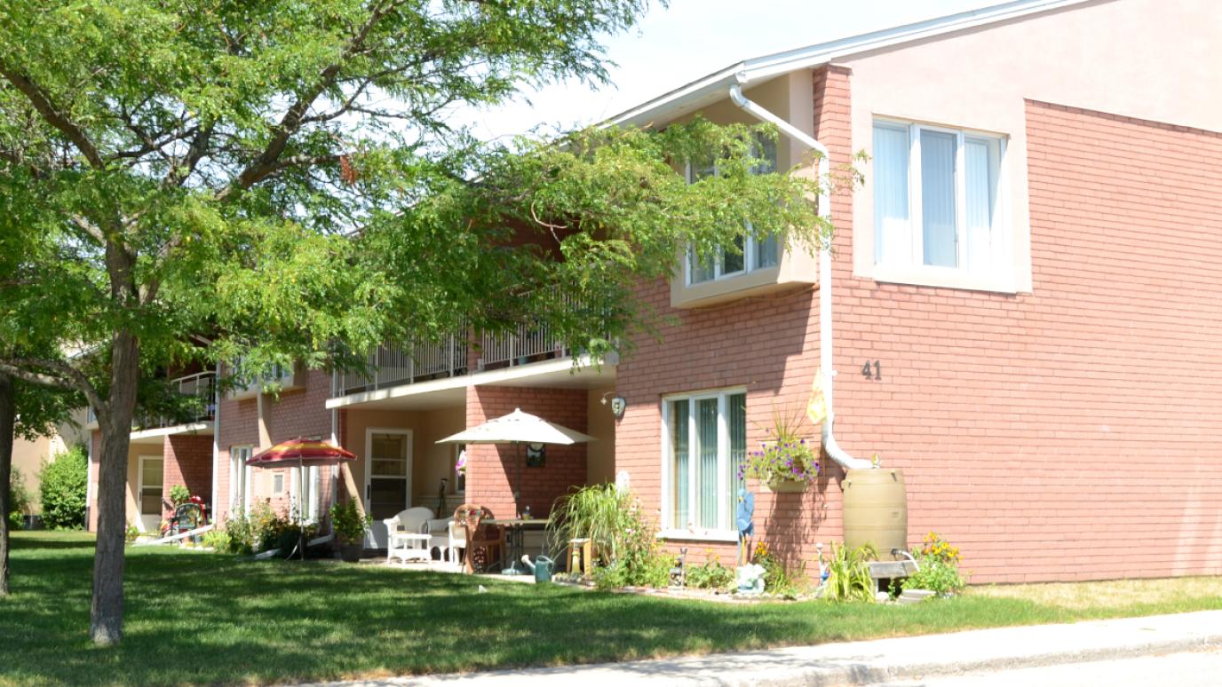 Exterior of 41 Cuthbert Street, Elora. It is a two-storey apartment building with a row of trees in front.
