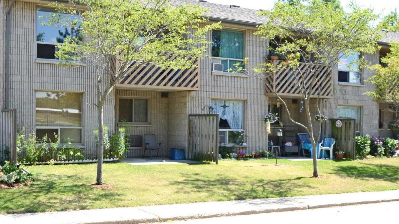 Exterior of 14 Centre Street, Erin. It is a two-storey apartment building with a row of small trees in front.