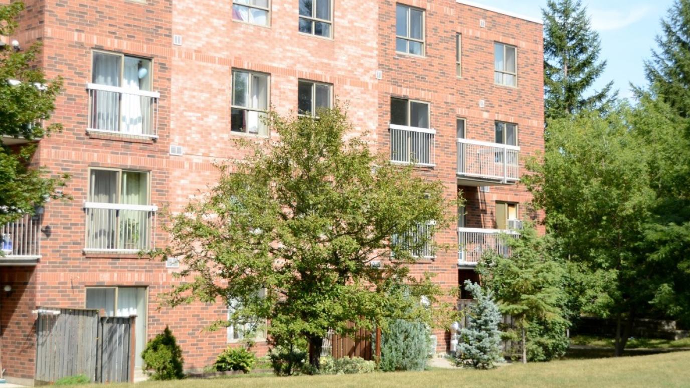 Exterior of 246 Westwood Road, Guelph. It is a four-storey apartment building surrounded by a lawn and trees.