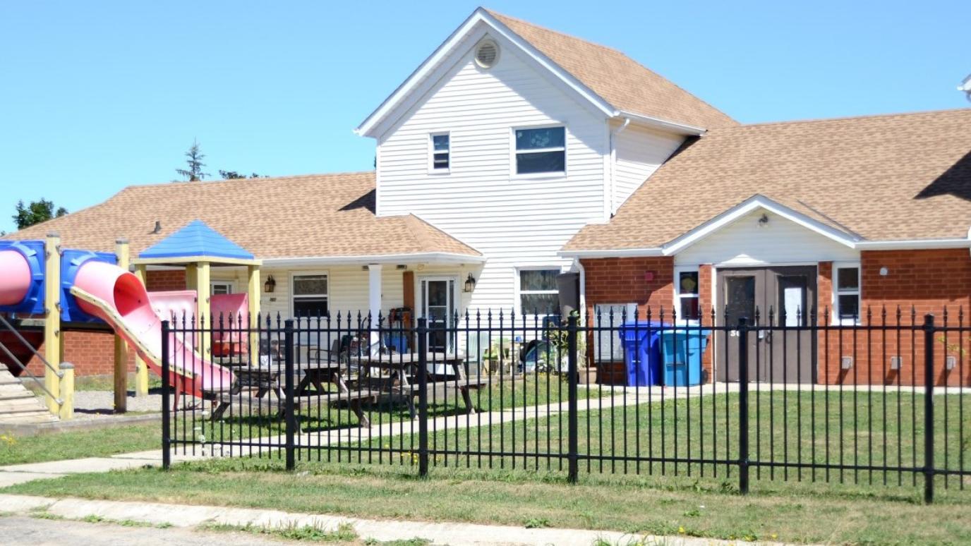 Exterior of 301 Tucker Street, Arthur. It is a townhouse with a play structure in front and a gate around it.
