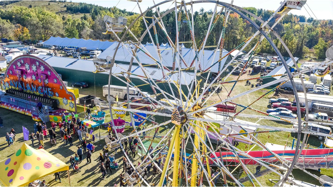 Colourful aerial photo of a large Ferris wheel spinning above the Erin Fall Fair grounds. 