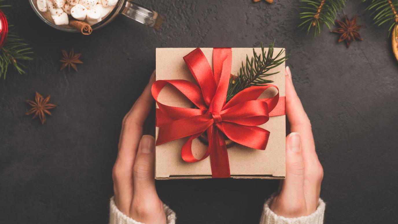 hands holding a gift box with a red bow