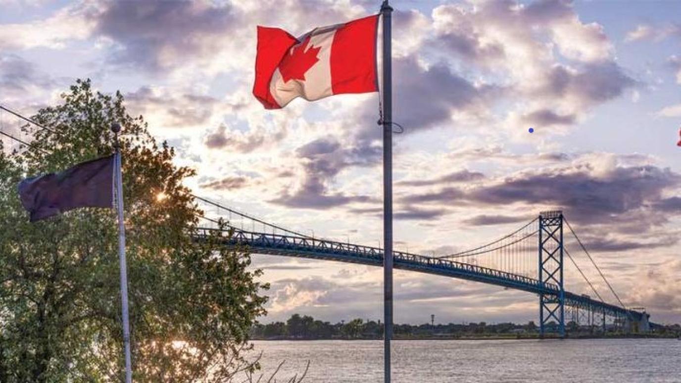 Photo overlooking the Ambassador Bridge where both the Canadian and American flags can be seen side by side, giving the impression of solidarity.