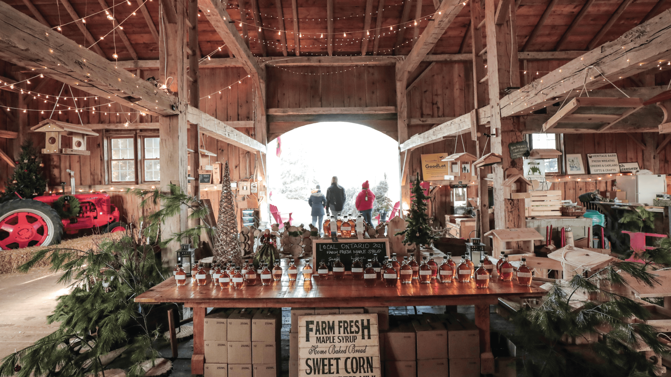 barn interior with high wooden ceilings and a bright arched doorway displaying maple products