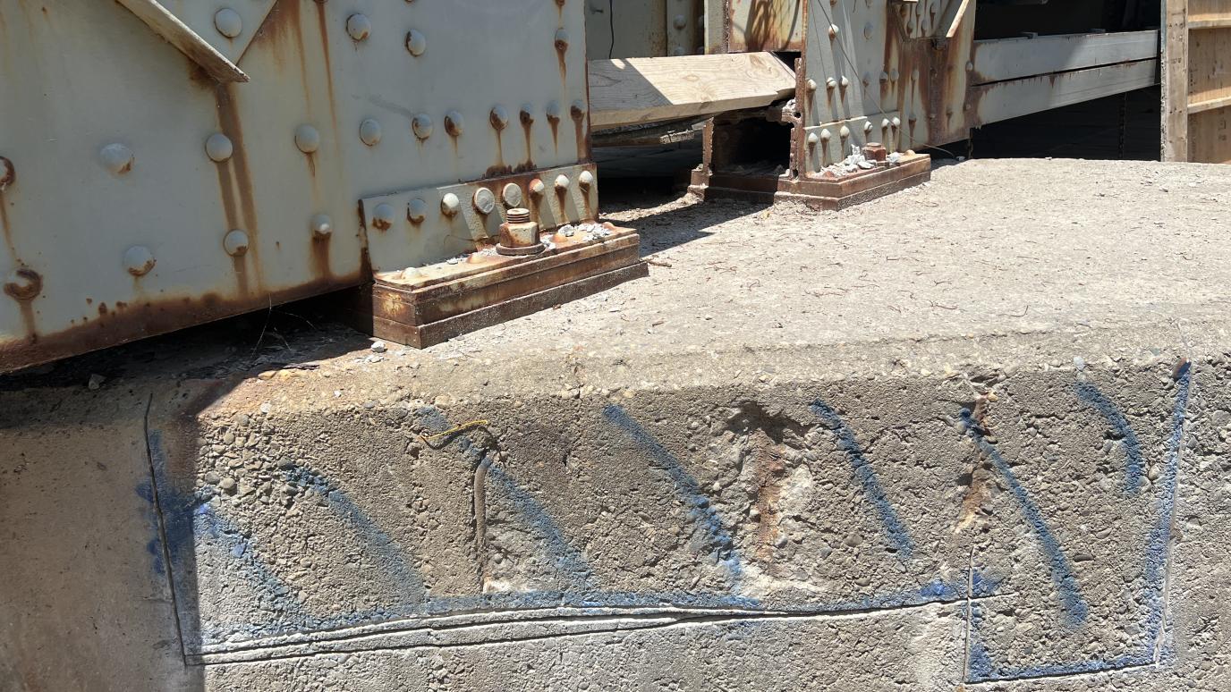 Close up of the concrete on Simmons Bridge with blue markings over old cracked concrete.