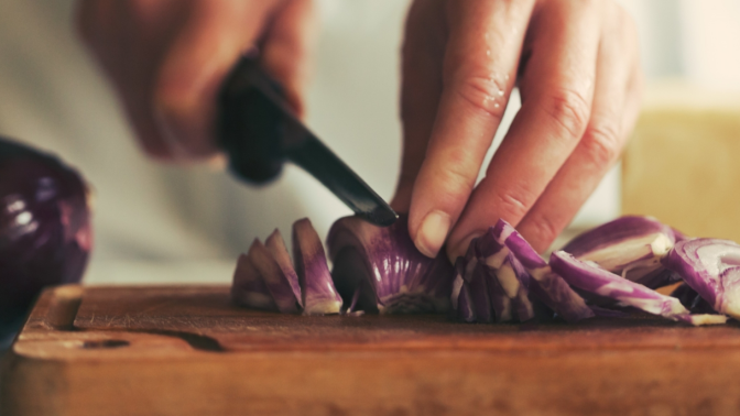 Onions being chopped on a chopping board