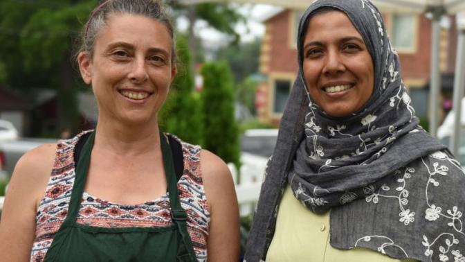 Two smiling female farmers selling products at a farmers market