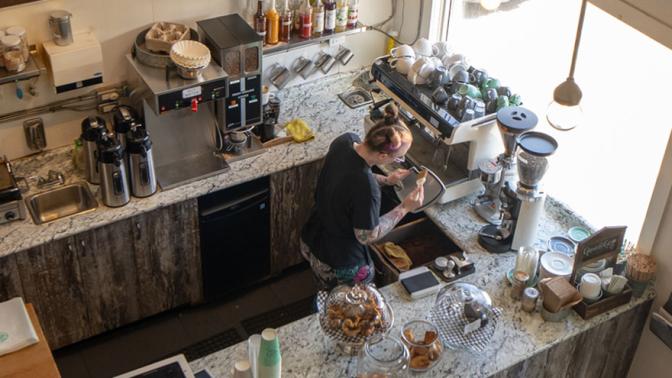 View from above of a barista preparing a drink behind the counter of a cafe