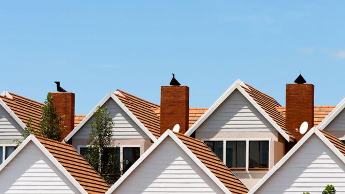 Close up detail of town house rooftops with chimneys against blue shy.