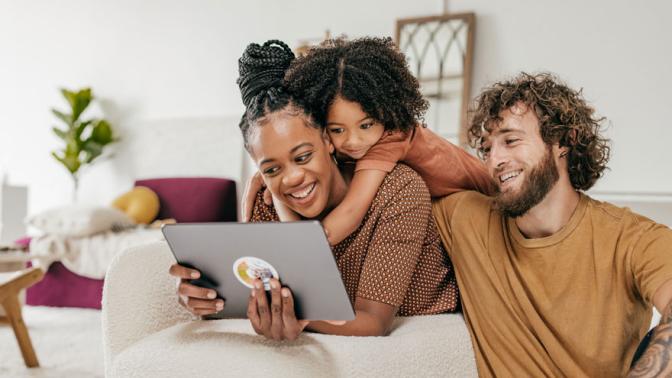 Smiling parents and daughter at home watching online movie together