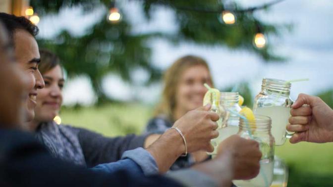Group of friends clinking their glasses together in cheers at an outdoor table