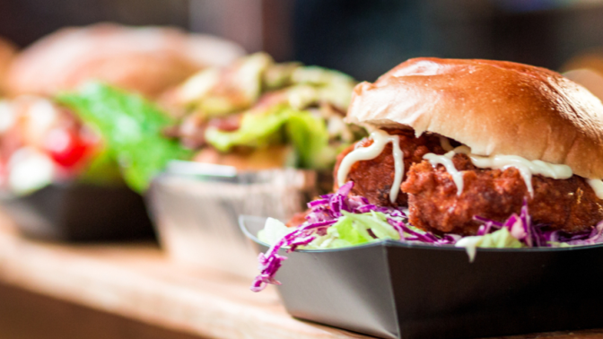 Row of delicious looking burgers lined up at a takeout counter