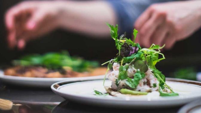 Chefs hands plating food dishes at a fine dining restaurant