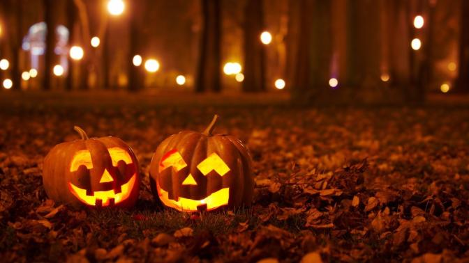 two jack-o-lantern pumpkins sitting on leaves