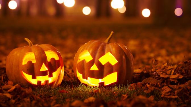two jack-o-lantern pumpkins sitting on leaves