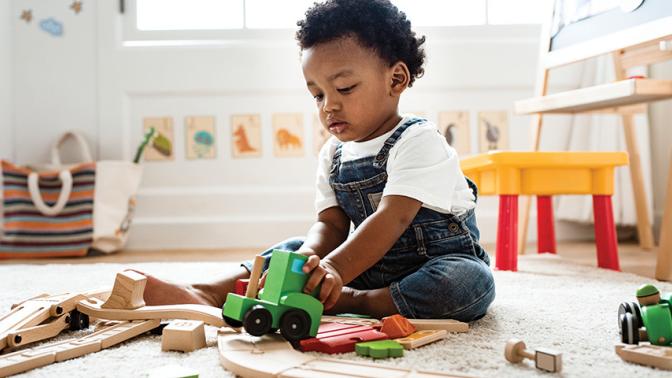 A small toddler plays in a room full of toys. 