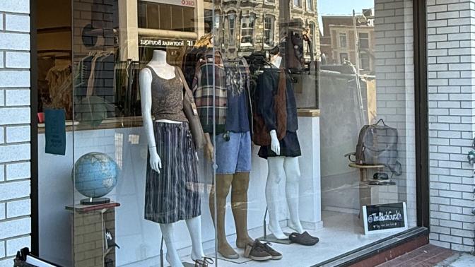 Storefront of "the Patch" clothing boutique featuring mannequins displayed in a large front window and an A-frame sign on the sidewalk.
