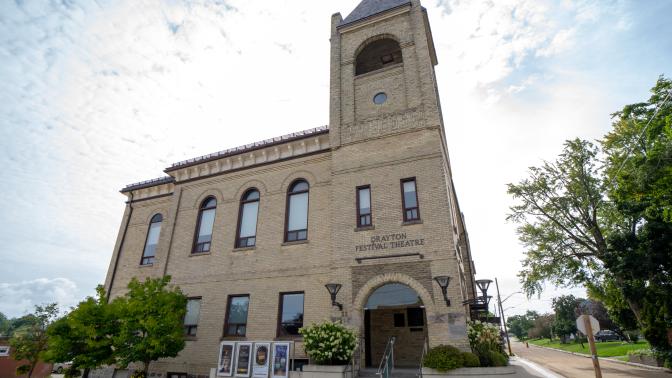 Historic theatre with a bell tower and arch entrance under a partly cloudy sky.