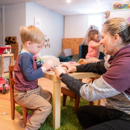 Child Care provider helping young boy at table