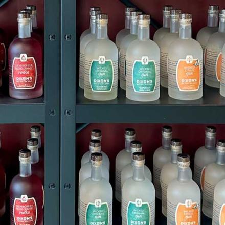 Shelving rack filled with perfectly alighted bottles of gin in an assortment of colours at Dixons Distillery
