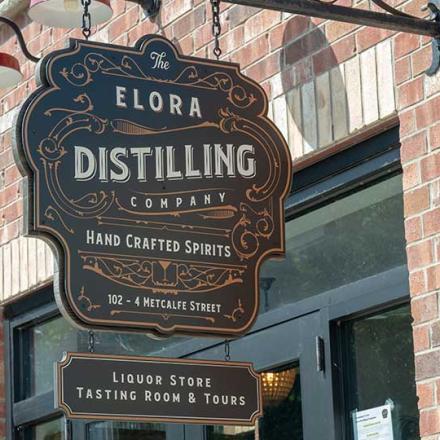 Decorative sign for Elora Distilling mounted on the front of their red brick building 