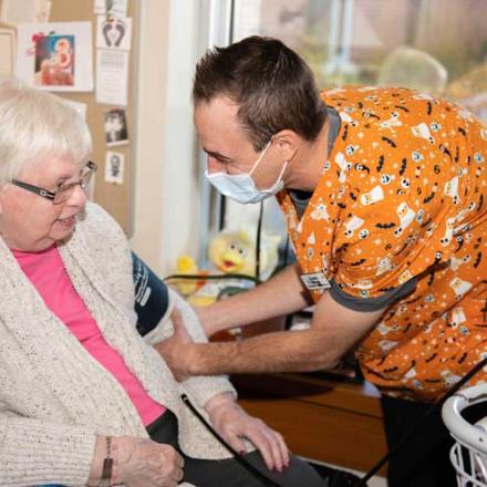 A smiling aide takes a residents blood pressure at the Wellington Terrace
