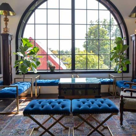 Seating area inside the Elora Distillery showcasing beautiful views through large arched windows and blue velvet benches.