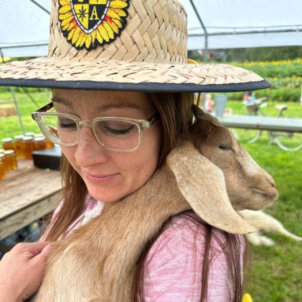 person in straw hat cuddling a goat