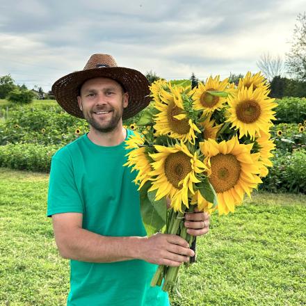 person wearing hat holding a large bouquet of sunflowers