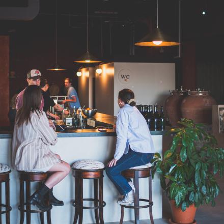 people sitting at a bar being served ciders by a bartender