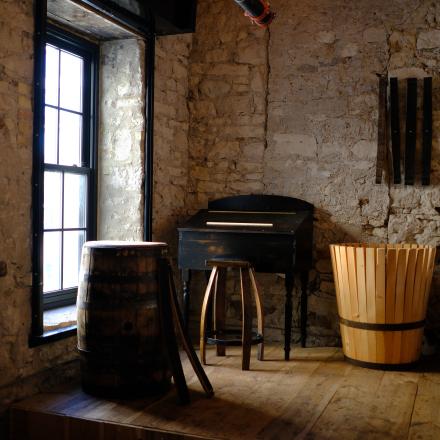 A dimly lit room with a wooden barrel close to a window