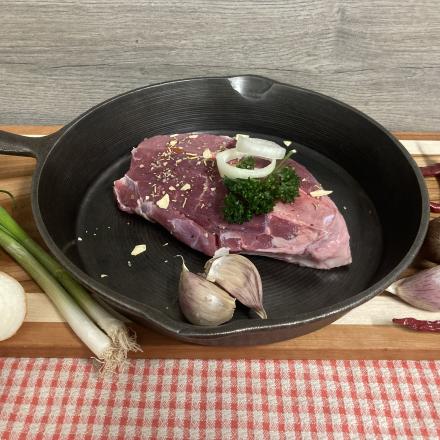 fresh cut steak in a pan with garlic and onion