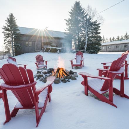 bonfire surrounded by red adirondack chairs in the snow outdoors