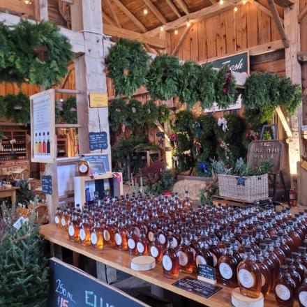 large indoor barn decorated with green wreaths and a long curved display of products