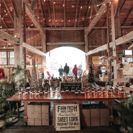 barn interior with high wooden ceilings and a bright arched doorway displaying maple products
