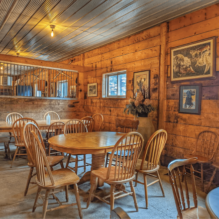 TR Elliott Tree Farm rustic dining room with wood walls and a round table