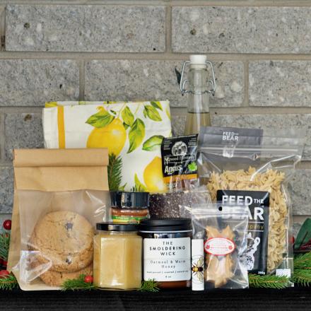 a gift basket of artisanal products, arranged on a dark surface in front of a gray brick wall