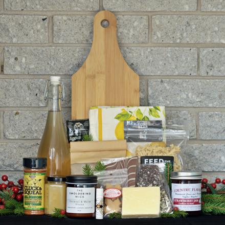 a gift basket of artisanal products, arranged on a dark surface in front of a gray brick wall