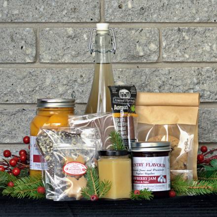 a gift basket of artisanal products, arranged on a dark surface in front of a gray brick wall