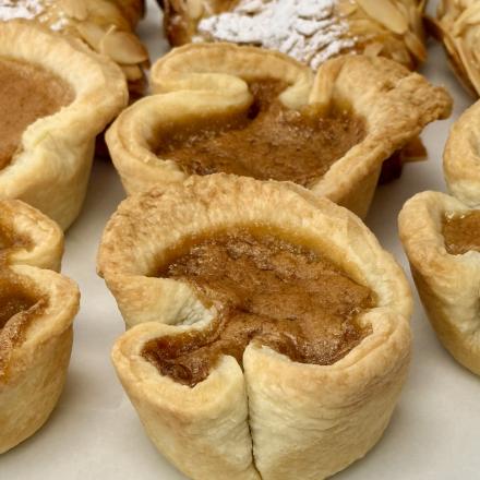 flaky butter tarts with almond croissants in the background