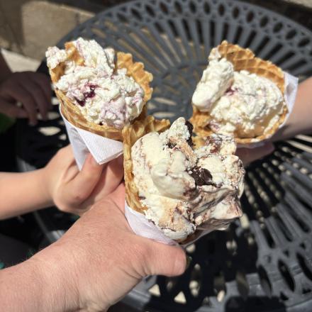hands holding scooped ice cream in waffle cones