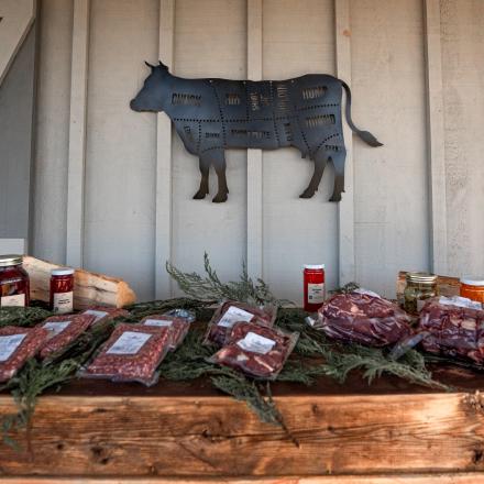 packaged farm meat displayed on a wooden table under a cow sign