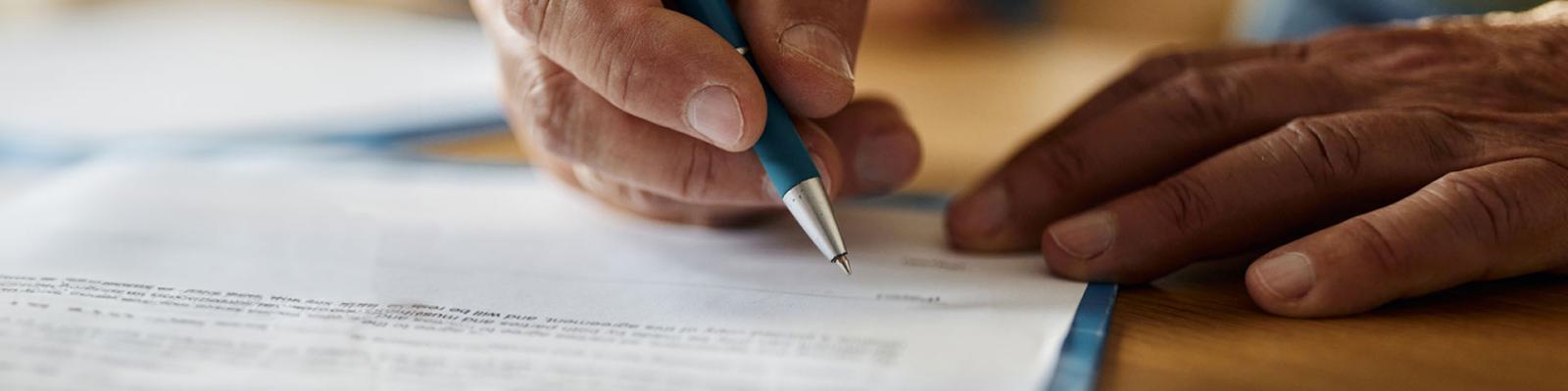 Close up of a persons hands singing a paper agreement form