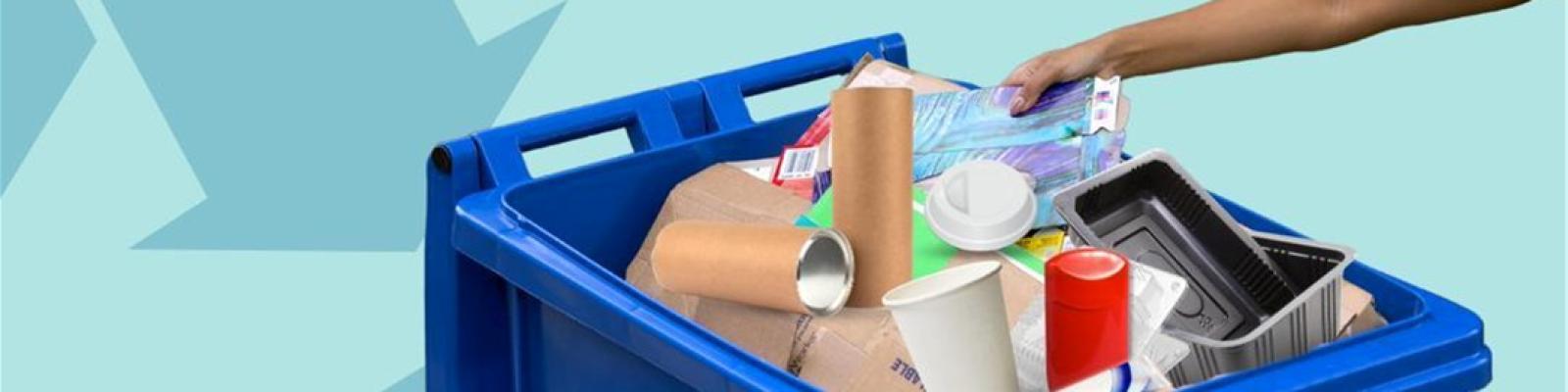 a person is setting recyclable material into a blue recycling cart