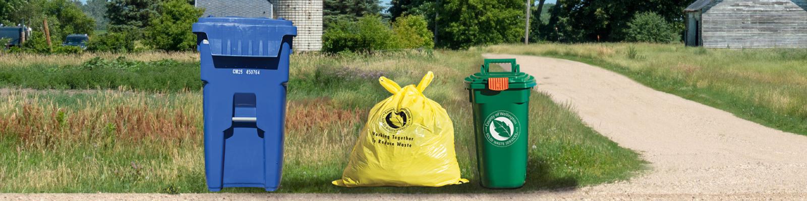 a recycling cart, yellow user pay garbage bag, and green bin sit at the end of a rural laneway