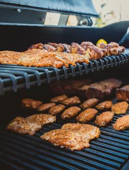 Close up of various meats cooking on a barbecue