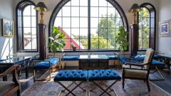Seating area inside the Elora Distillery showcasing beautiful views through large arched windows and blue velvet benches.