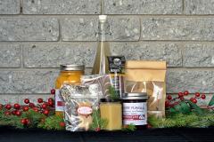 a gift basket of artisanal products, arranged on a dark surface in front of a gray brick wall