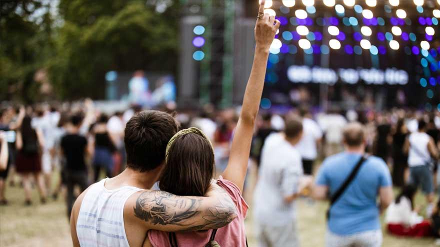 A couple from behind embracing while enjoying music at an outdoor concert
