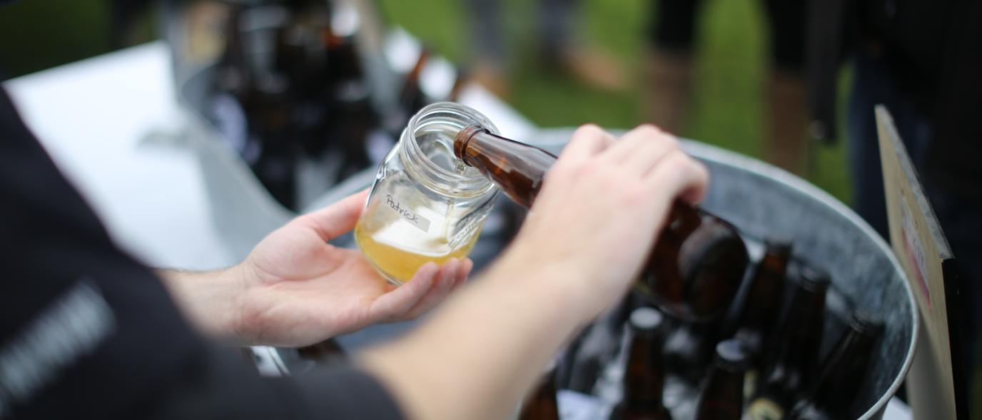 A person pouring a drink in a glass jar